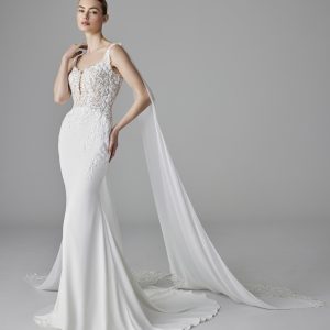 Bröllopsklänning Alix med figurnär passform, spetsliv och flytande axelkappa – elegant design med modern detaljrikedom.