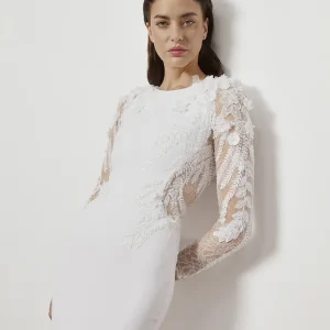 Bröllopsklänning Justine med långärmade spetsdetaljer och figurnära siluett – modern elegans med illusionstyll och broderade bladmönster.