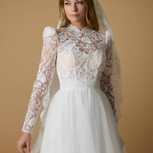 Romantisk brudklänning Meish från Nicole Milano med långärmat spetsliv, hög krage och voluminös tyllkjol – klassisk och kunglig stil.
